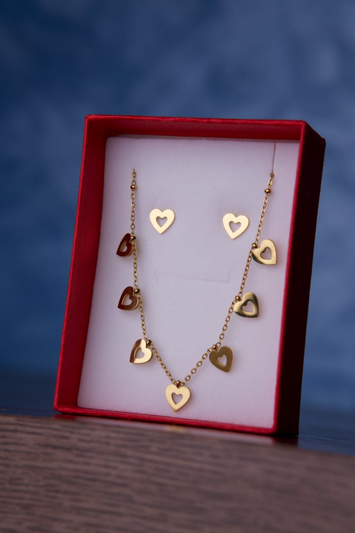 Services Elegant gold heart necklace and earrings set displayed in a red box, perfect gift for special occasions.