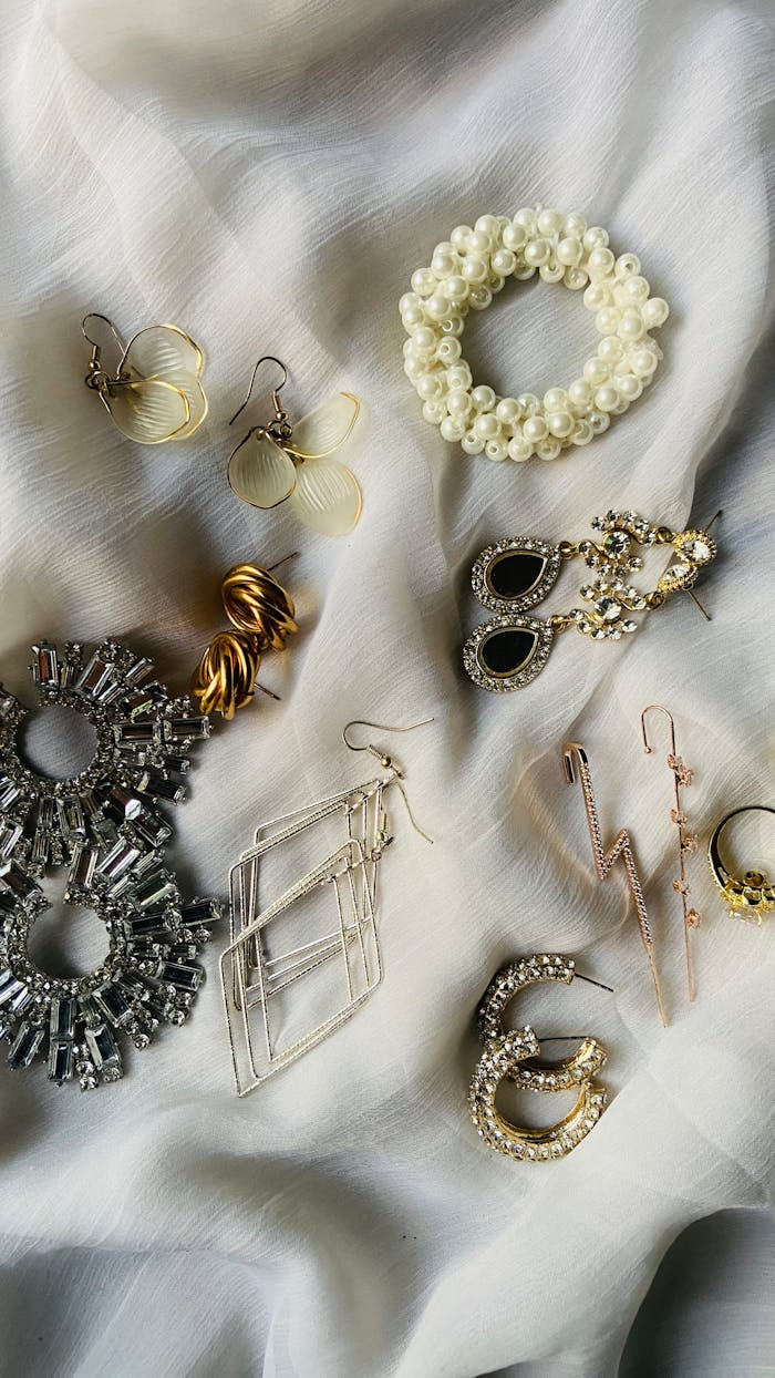 Home A stylish display of various earrings and jewelry pieces on a white fabric background.