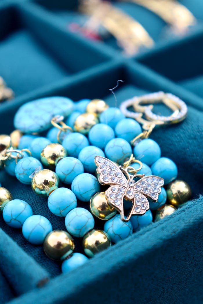Home Close-up of turquoise and gold bead bracelet with a crystal butterfly charm in a jewelry box.